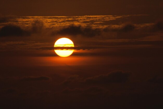 Un soleil orange vif est allumé contre un ciel sombre.