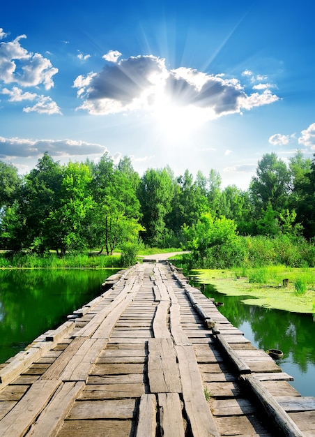 Soleil sur pont de bois à travers la rivière calme