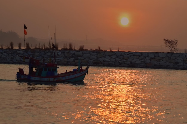 Le soleil se couche En mer il y a des bateaux de pêche qui passent