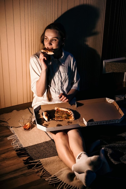 Solitude dans les vacances de noël saint valentin jeune femme seule en pyjama mangeant de la pizza près de