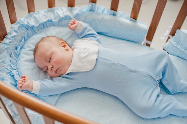 Le sommeil réparateur de bébé. Nouveau-né dans un berceau en bois. Le bébé dort dans le berceau de chevet.