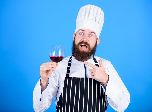 Sommelier au travail Boisson alcoolisée Vin rouge en verre Heureux homme barbu Chef professionnel en uniforme de cuisinier Ce vin est tout simplement parfait Sommelier masculin confiant examinant le verre avec du vin