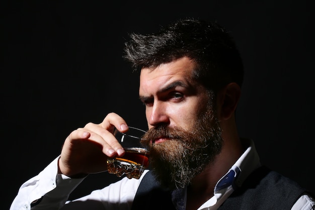 Le sommelier goûte une boisson chère. Homme d'affaires barbu en costume élégant avec verre de cognac. Concept de dégustation et de dégustation de vin.