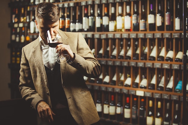 Sommelier masculin dégustant du vin rouge à la cave