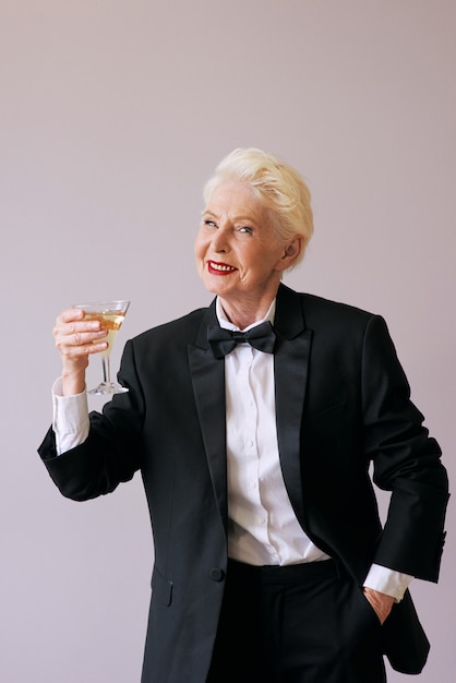 Sommelier mature élégant senior woman in tuxedo avec verre de vin mousseux