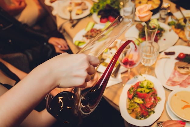 Sommelier verser le vin dans le verre du bol à mélanger au dîner de luxe.