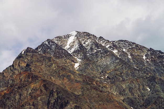 Sommet de la montagne enneigée dans le ciel nuageux