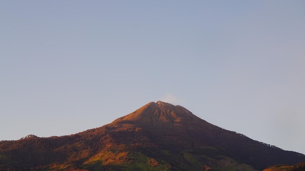 Un sommet de montagne avec un nuage de fumée s'élevant du sommet.