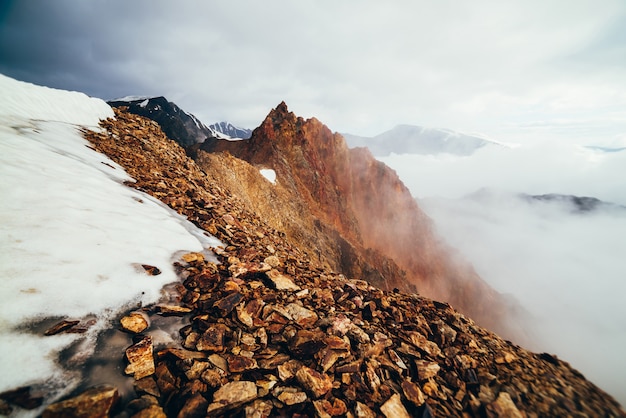 Sommet de la montagne rocheuse nette au-dessus des nuages épais