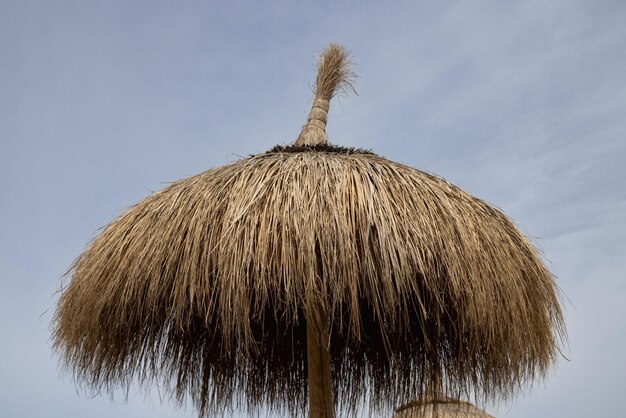 Le sommet d'un parapluie de roseau sur la plage contre un ciel nuageux