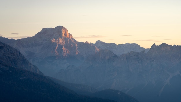 Photo le sommet rocheux de la chaîne de montagnes capture la première lumière au lever du soleil.