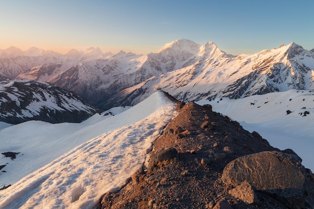 Sommets enneigés au lever du soleil avec bord de montagne sombre au premier plan Caucase Russie