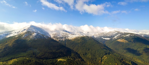 Des sommets de haute montagne recouverts d'une forêt d'épicéas d'automne et de hauts sommets enneigés.