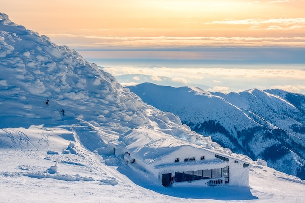 Sommets d'hiver des montagnes dans la matinée ensoleillée. Léger brouillard dans les vallées. Snow Cafe et deux touristes méconnaissables