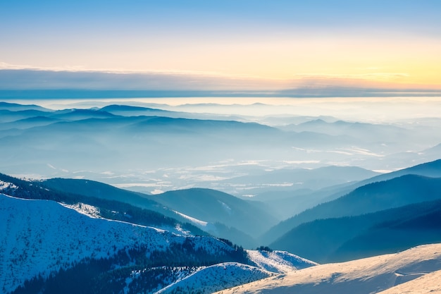 Les sommets des montagnes d'hiver et un léger brouillard dans les vallées. Temps ensoleillé et ciel bleu