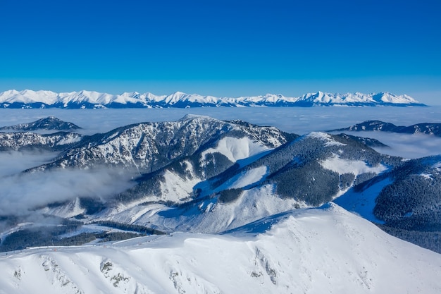 Les sommets des montagnes hivernales et la brume matinale dans les vallées. Temps ensoleillé et ciel bleu