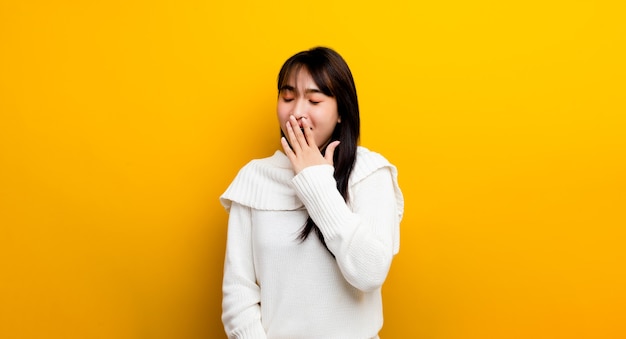 Somnolence. Belle femme asiatique. Portant un pull, endormi et bâillant est fatigué, couvrant sa bouche avec ses mains. agité et somnolent