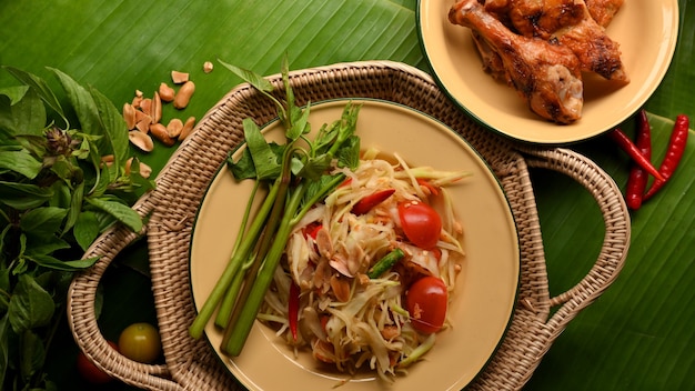 Somtum ou salade de papaye avec poulet grillé à la thaïlandaise et légumes sur fond de feuilles de bananier Cuisine thaïlandaise