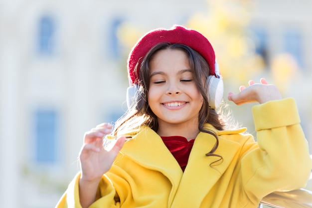 Son stéréo. Bonnes vibrations seulement. Tenue d'automne fille enfant appréciant la musique. Son génial. Enfant fille avec un fond urbain de casque. Petite fille écoutant de la musique, profitez d'un excellent son de la chanson préférée.