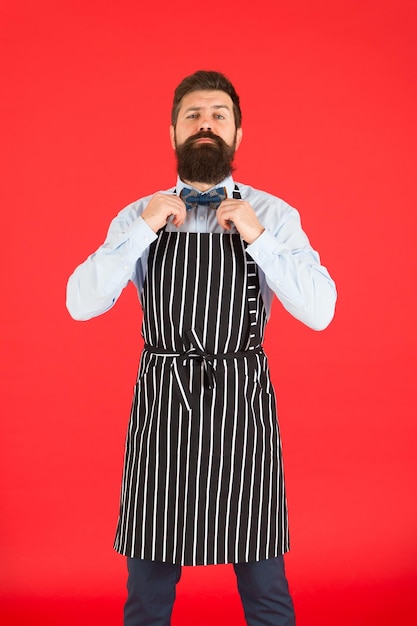 Son style fonctionne très bien pour complimenter la barbe Homme barbu fixant un nœud papillon dans un tablier à bavette Hipster élégant avec un visage barbu Barman barbu ou cuisinier en uniforme de travail Serveur ou serviteur barbu long