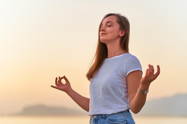 Soncentré heureux serein satisfait une femme calme debout seule avec une position de méditation tout en respirant l'exercice Soins de santé de l'esprit mental et moment de soulagement