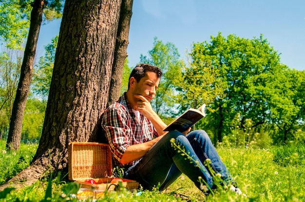 Songeur jeune homme lisant un livre