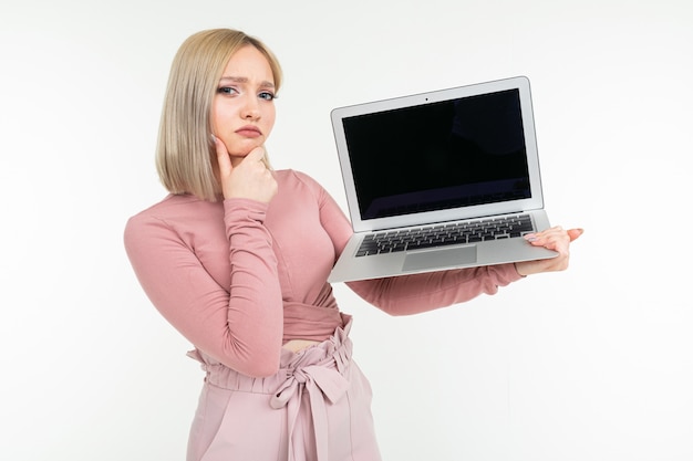 Songeuse jeune femme élégante détient un écran blanc pour ordinateur portable pour site Web sur fond blanc