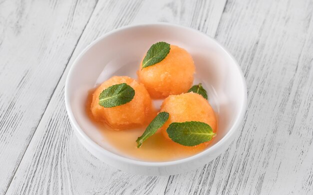 Sorbet cantaloup-menthe avec des feuilles de menthe fraîche dans le bol blanc