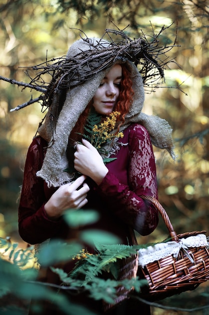 La sorcière aux cheveux roux organise un rituel avec une boule de cristal dans la forêt