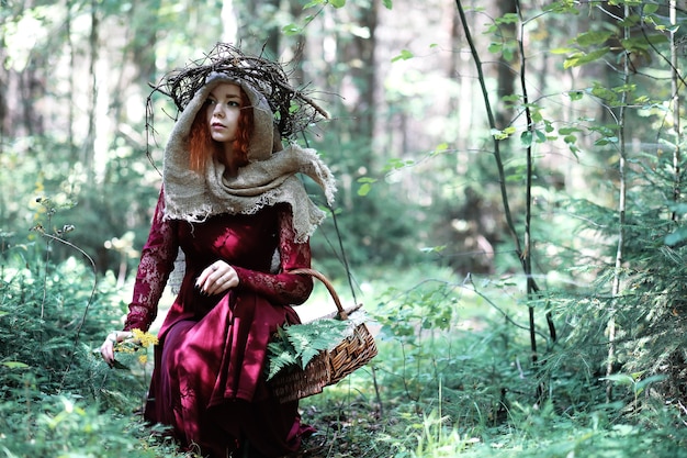 La sorcière aux cheveux roux organise un rituel avec une boule de cristal dans la forêt