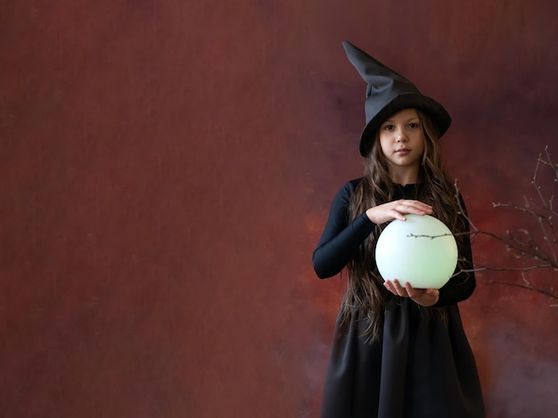 La sorcière avec une boule magique dans ses mains provoque un esprit dans la grotte