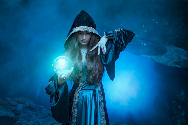 Photo la sorcière avec une boule magique dans ses mains provoque un esprit dans la grotte