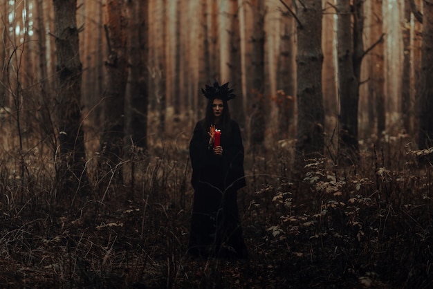 La Sorcière En Costume Noir Effectue Des Sorts Sombres Avec Des Bougies Dans La Forêt