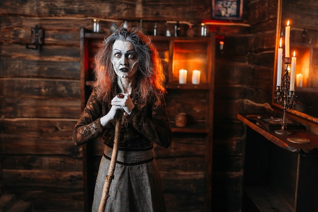 Une sorcière effrayante avec une canne au miroir et des bougies.