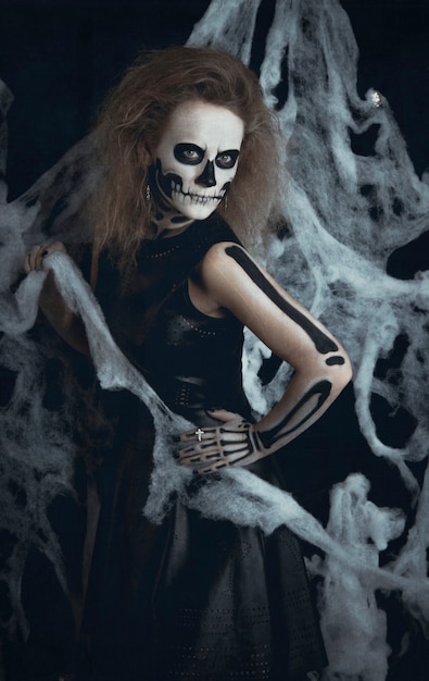 Sorcière squelette fille posant dans les toiles, Halloween. La sorcière se prépare pour la nuit des morts