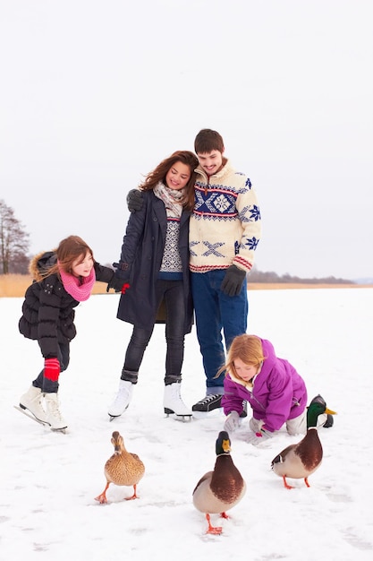 Une sortie hivernale Boutique d'un couple heureux et de leurs enfants jouant avec des oies lors d'une journée d'hiver dans la neige