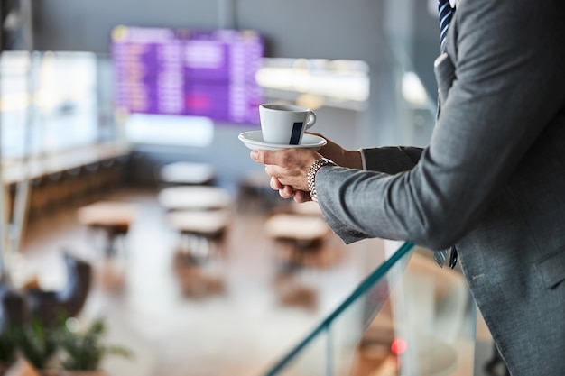 Soucoupe blanche avec une tasse dans les mains de l'homme d'affaires