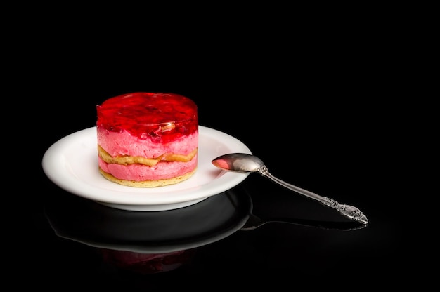 Soucoupe avec gâteaux et cuillère à café sur fond noir.