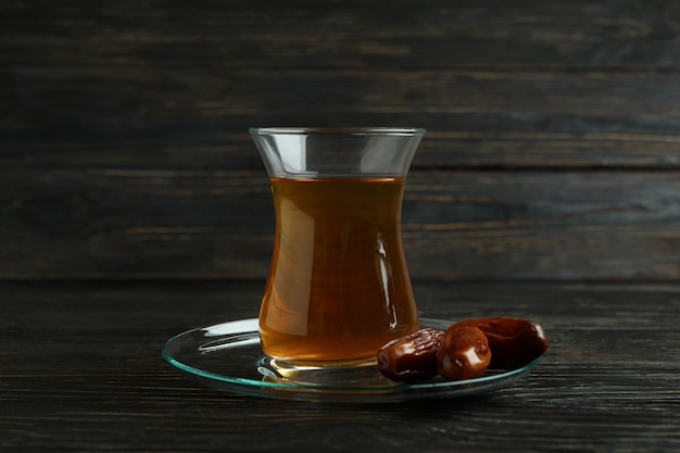 Soucoupe avec verre de thé et dattes sur une surface en bois