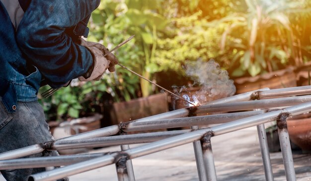 Le soudeur soude le cadre en acier. La main-d'œuvre et l'industrie travaillent dur.