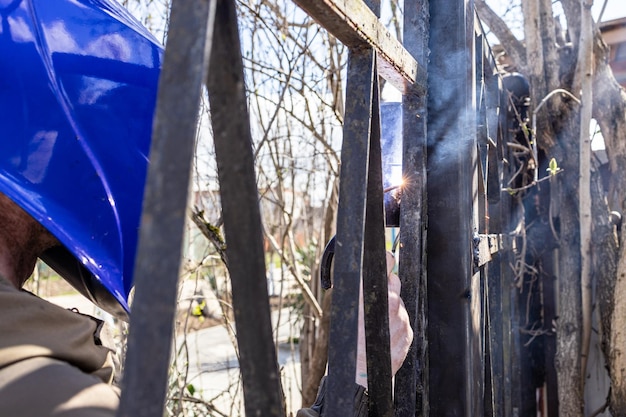 Le soudeur soude la charnière sur la porte avec l'électrode de soudure