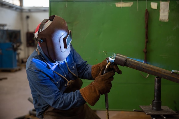 Un soudeur soude un morceau de métal dans le travail industriel d'usine