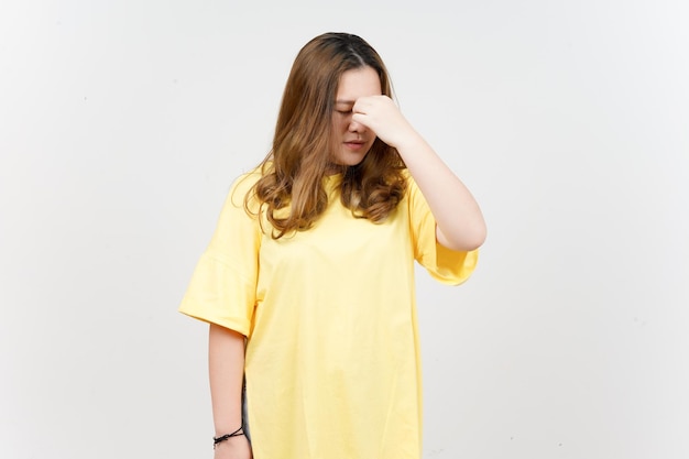 Souffrant de maux de tête de belle femme asiatique portant un T-shirt jaune isolé sur fond blanc