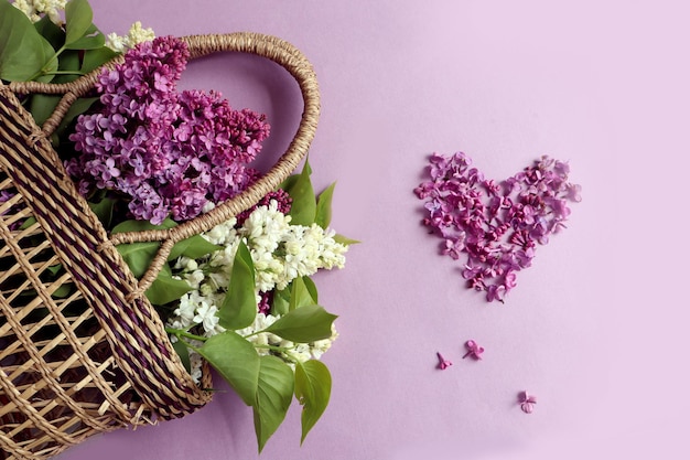 Souhaits pour une bonne journée un panier avec des branches lilas un coeur de fleurs lilas sur un fond pastel vue de dessus espace pour le texte