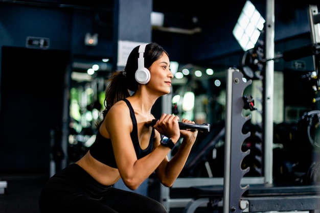 soulever des haltères exercices de bras jeune femme portant des écouteurs pendant l'exercice