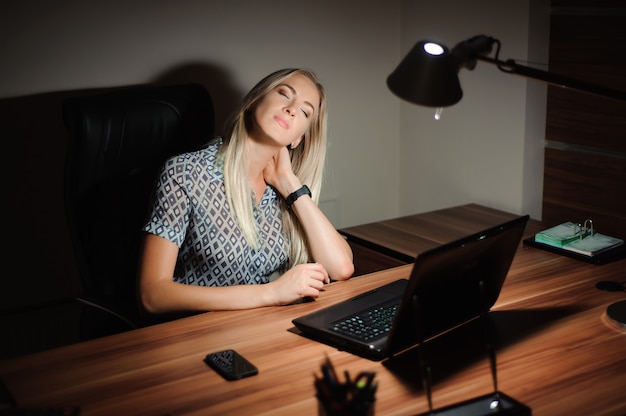 Souligne la femme d'affaires assis au bureau et pense à la solution tout en travaillant tard devant un ordinateur.