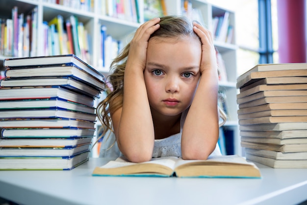 A souligné la fille avec des livres à table dans la bibliothèque de l'école