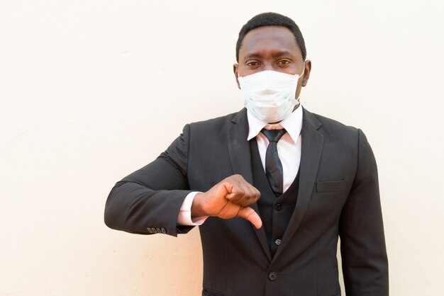 A souligné l'homme d'affaires africain avec masque donnant les pouces vers le bas sur fond blanc