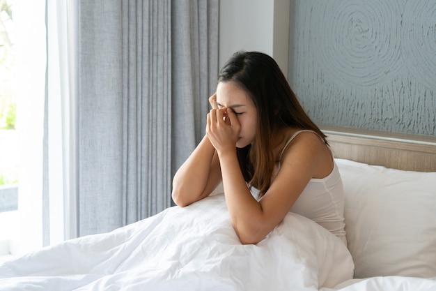 A souligné une jeune femme asiatique souffrant de dépression et assise seule dans sa chambre à la maison. concept triste, malheureux, déçu