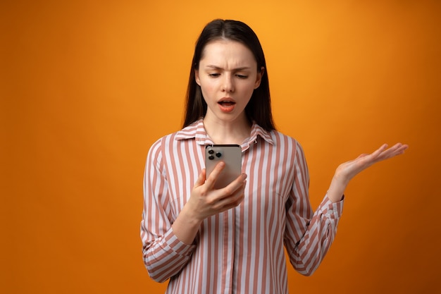 A souligné la jeune femme frustrée tenant un smartphone a reçu de mauvaises nouvelles sur fond jaune